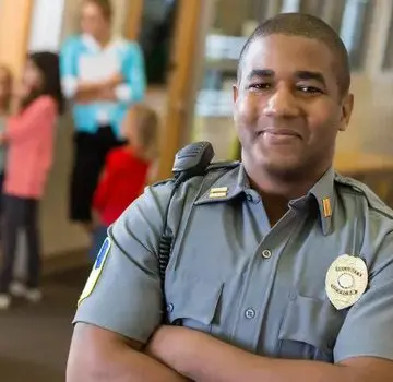 A police officer smiling for the camera with his arms crossed.