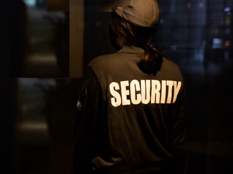 A person in black jacket standing next to window.