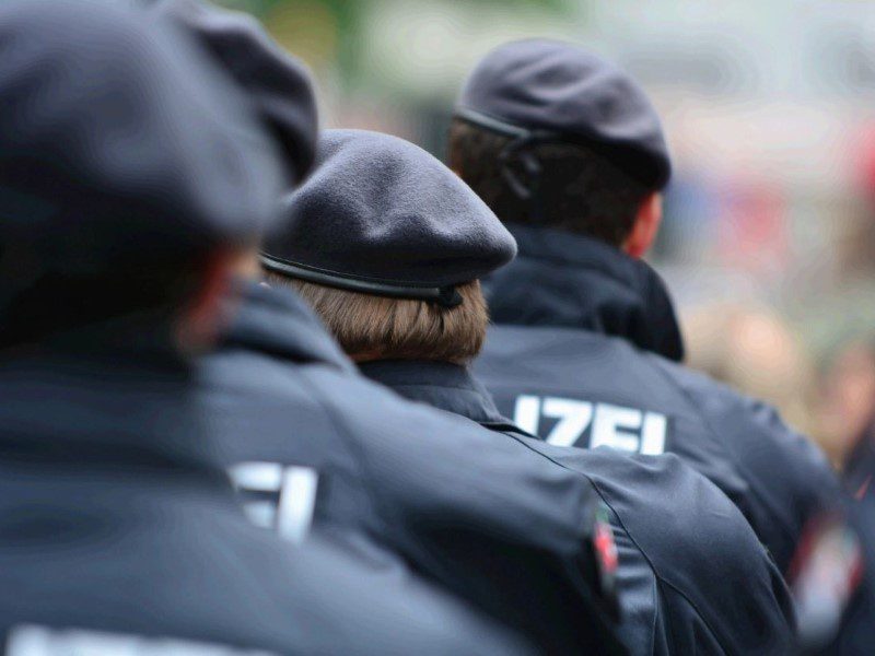 A group of people in black jackets and hats.