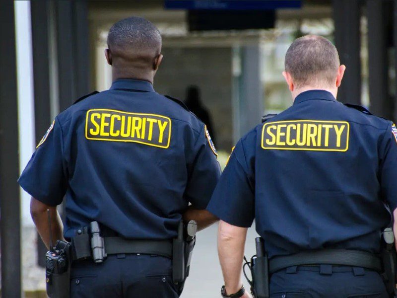 Two security guards are walking down the street.